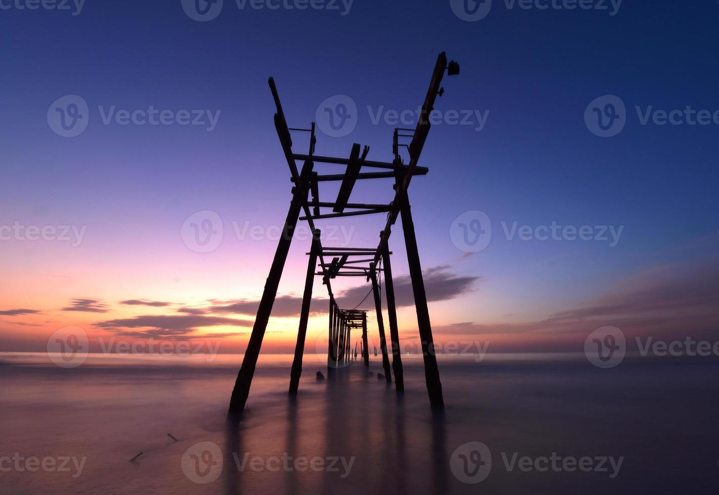 Scene of beautiful sunset and old wooden bridge at Pilai beach photo