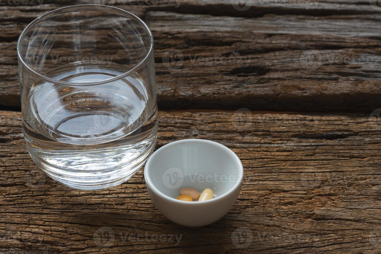 Medications in white container and a glass of water photo