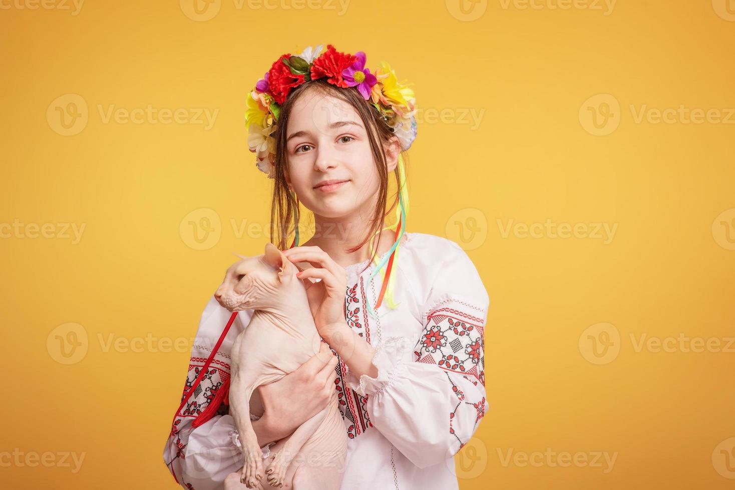 Teen girl with a wreath on her head and dressed in an embroidered shirt with a cat in her arms. Pet. photo