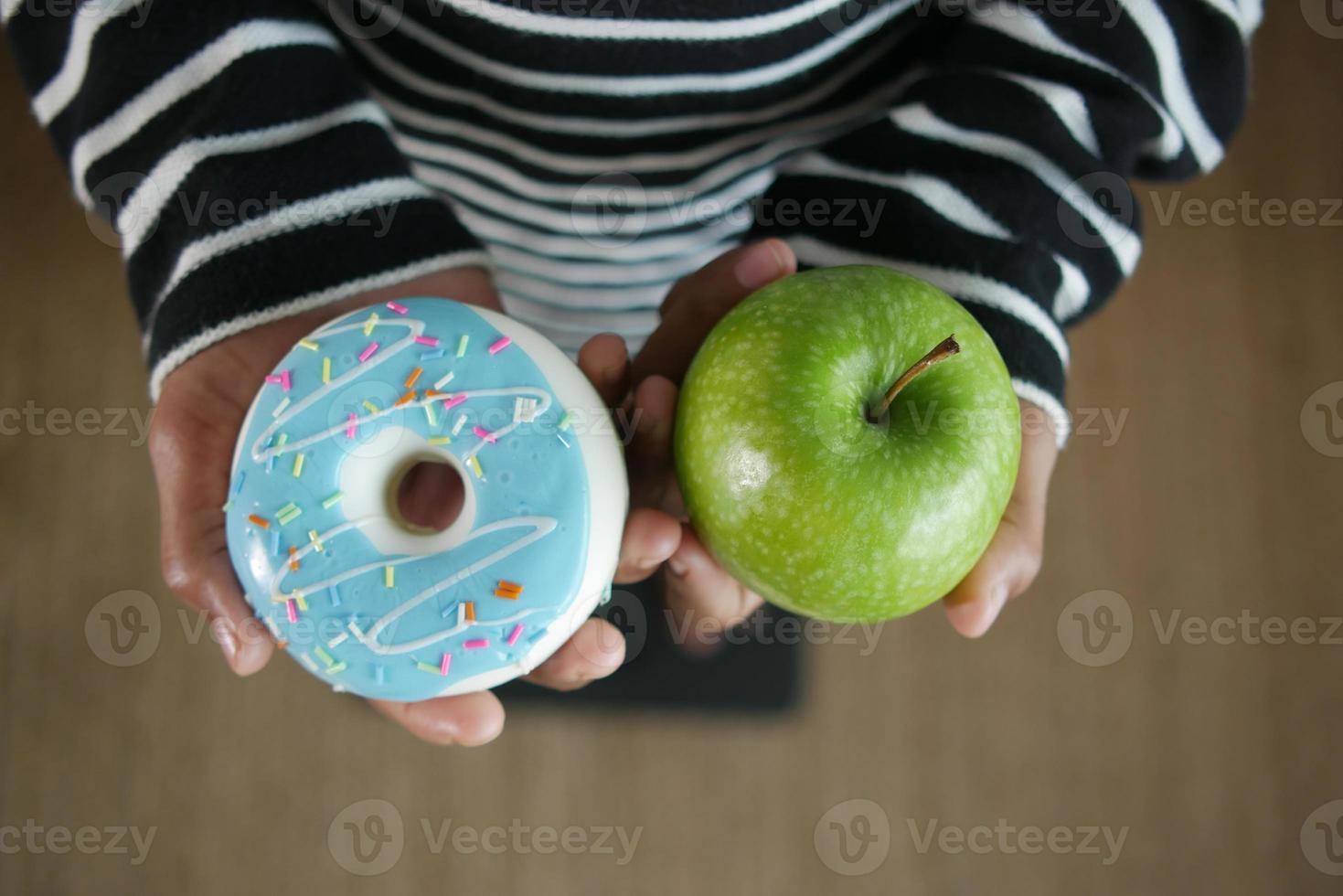 hand holding donuts and apple on hand on weight scale . photo
