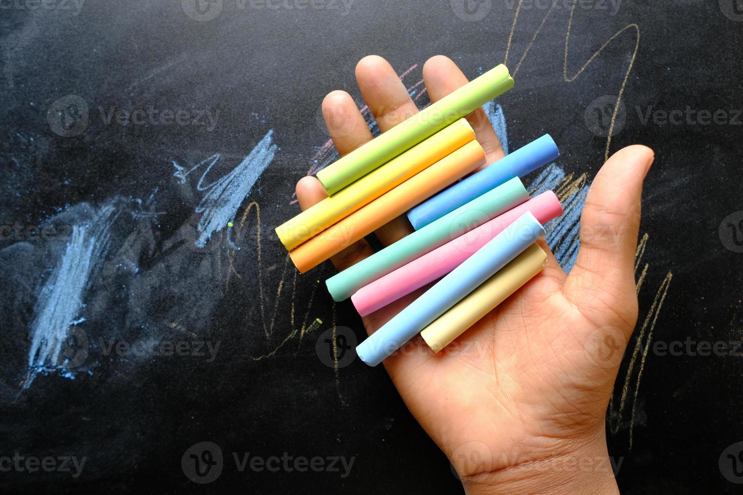 child holding many colorful chalk top view photo