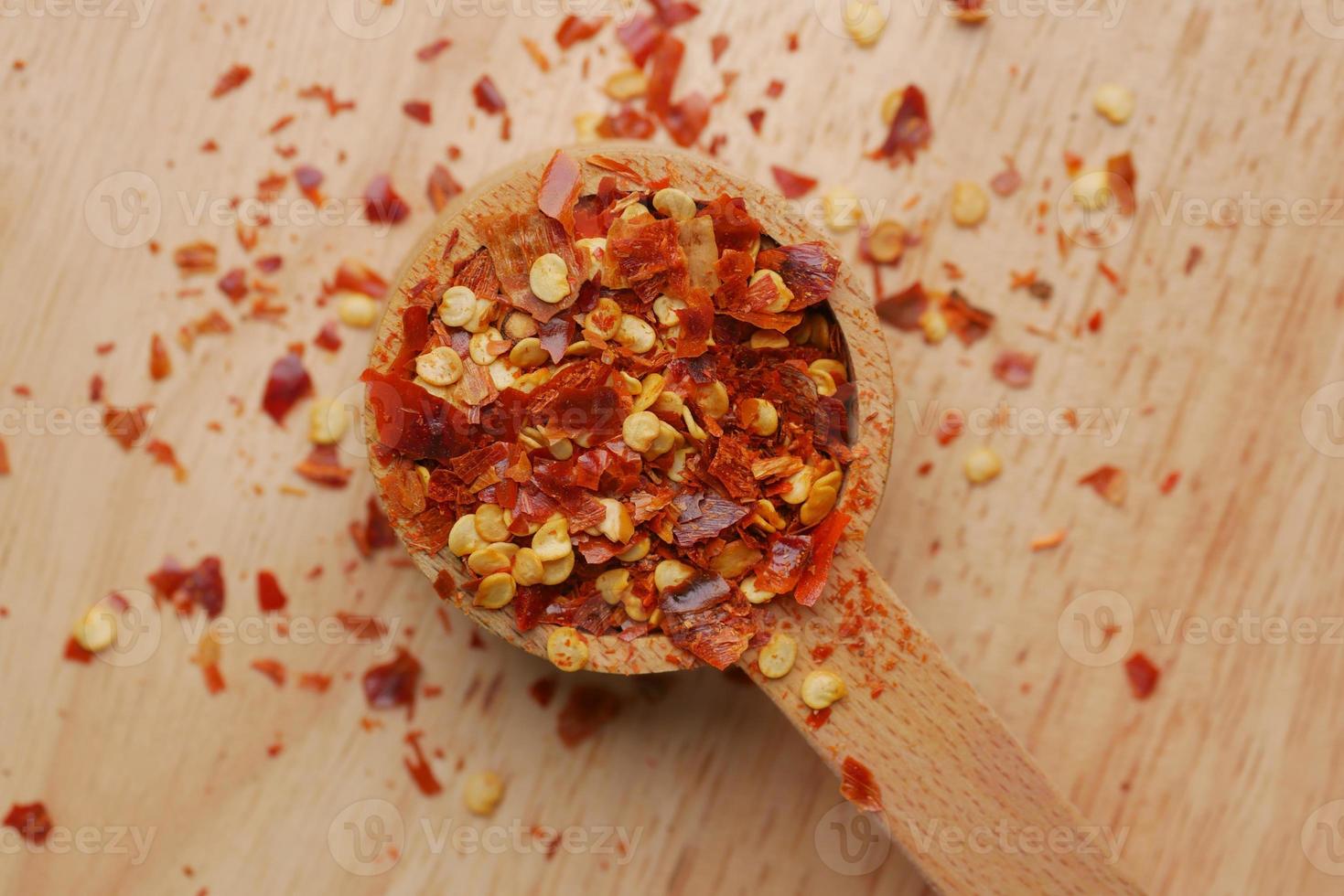 red chili pepper flakes in wooden spoon photo