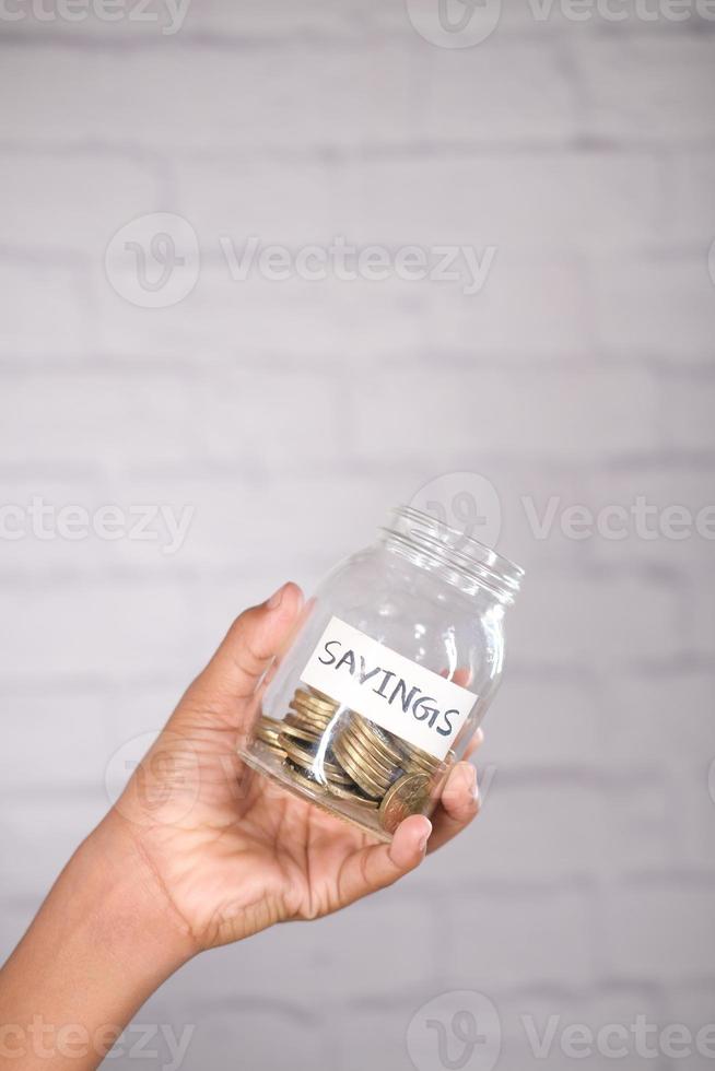 child boy hand hold a saving coins jar photo