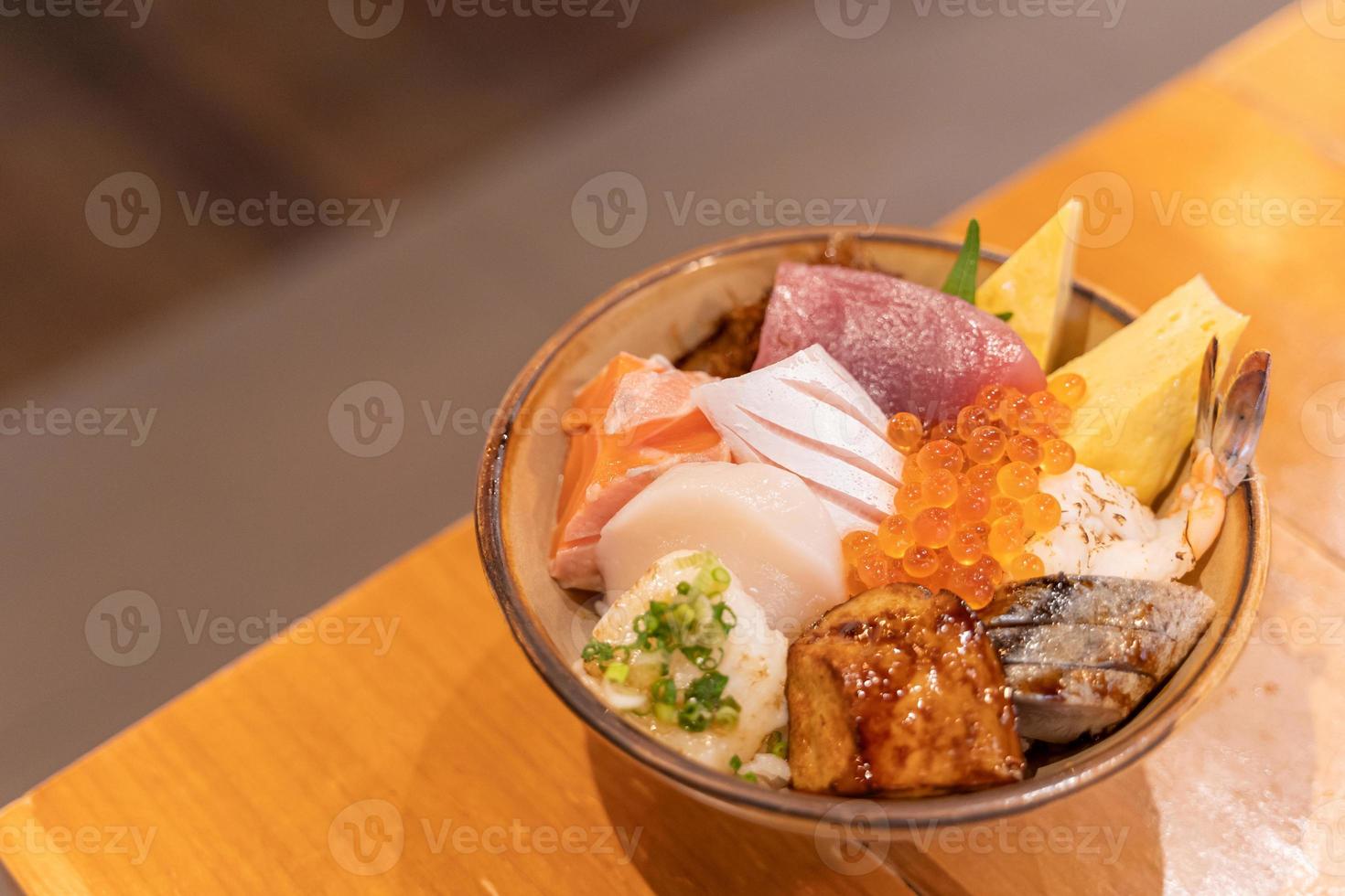 Top view of Sashimi Don, Donburi or Japanese rice bowl with various raw fresh slice of fish, shrimp, squid and tamago egg. mixed fresh sea food on rice in ceramic of Japanese tradition cuisine food. photo