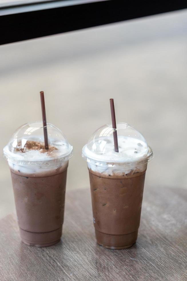 dos helados de chocolate o café moca en un vaso para llevar cubierto con crema de espuma de leche en el café foto
