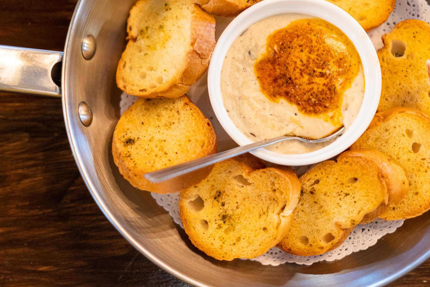 Selective focus, Cheese dip with butter and garlic bread slices. Fresh golden toasts served with cheesy sauce. top view photo