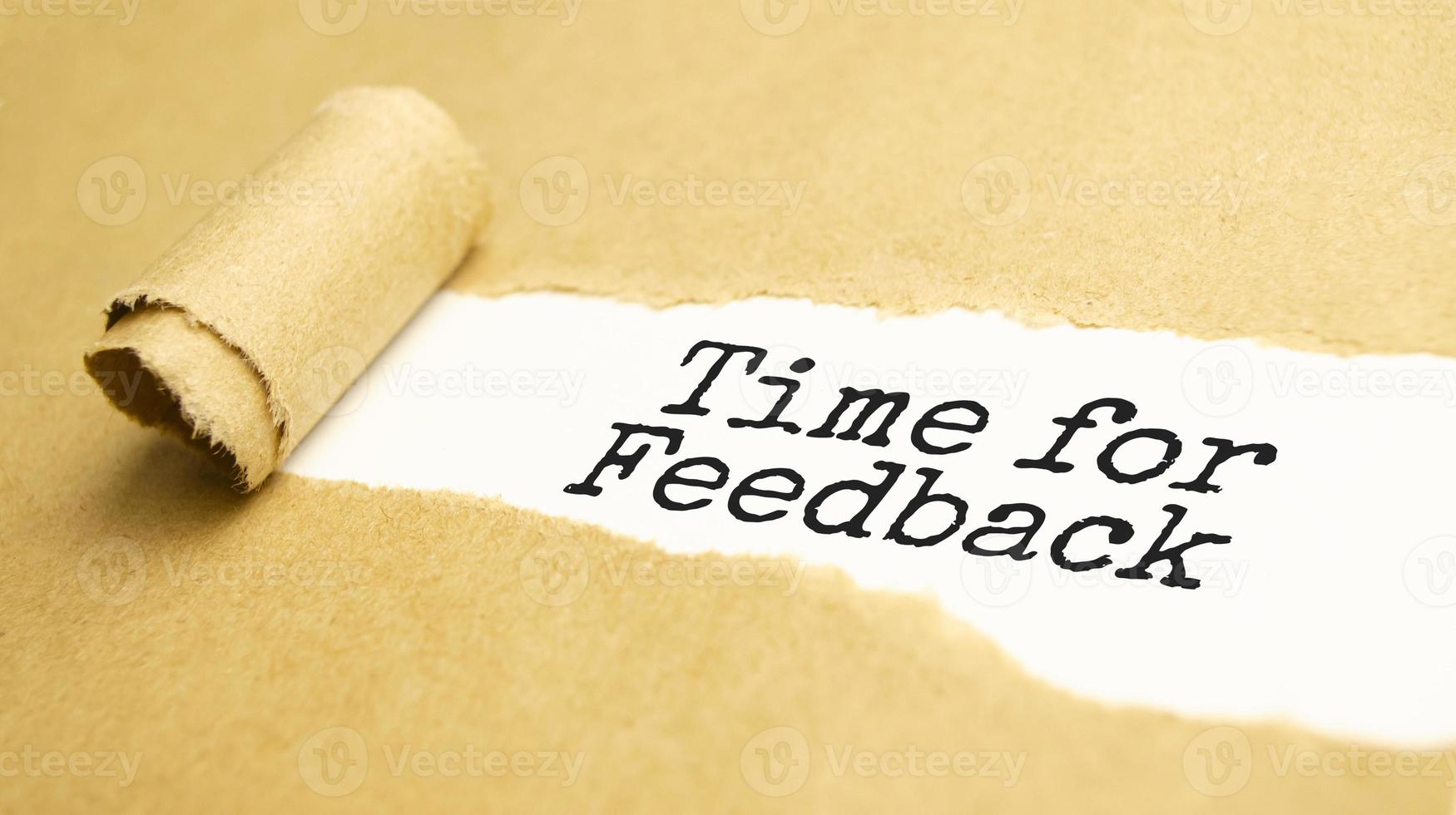 The text time for feedback appearing behind torn brown paper photo