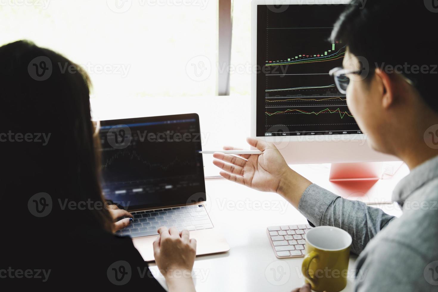 An investment expert points a pen at a computer monitor to analyze the stock market to teach you how to make a profit. photo