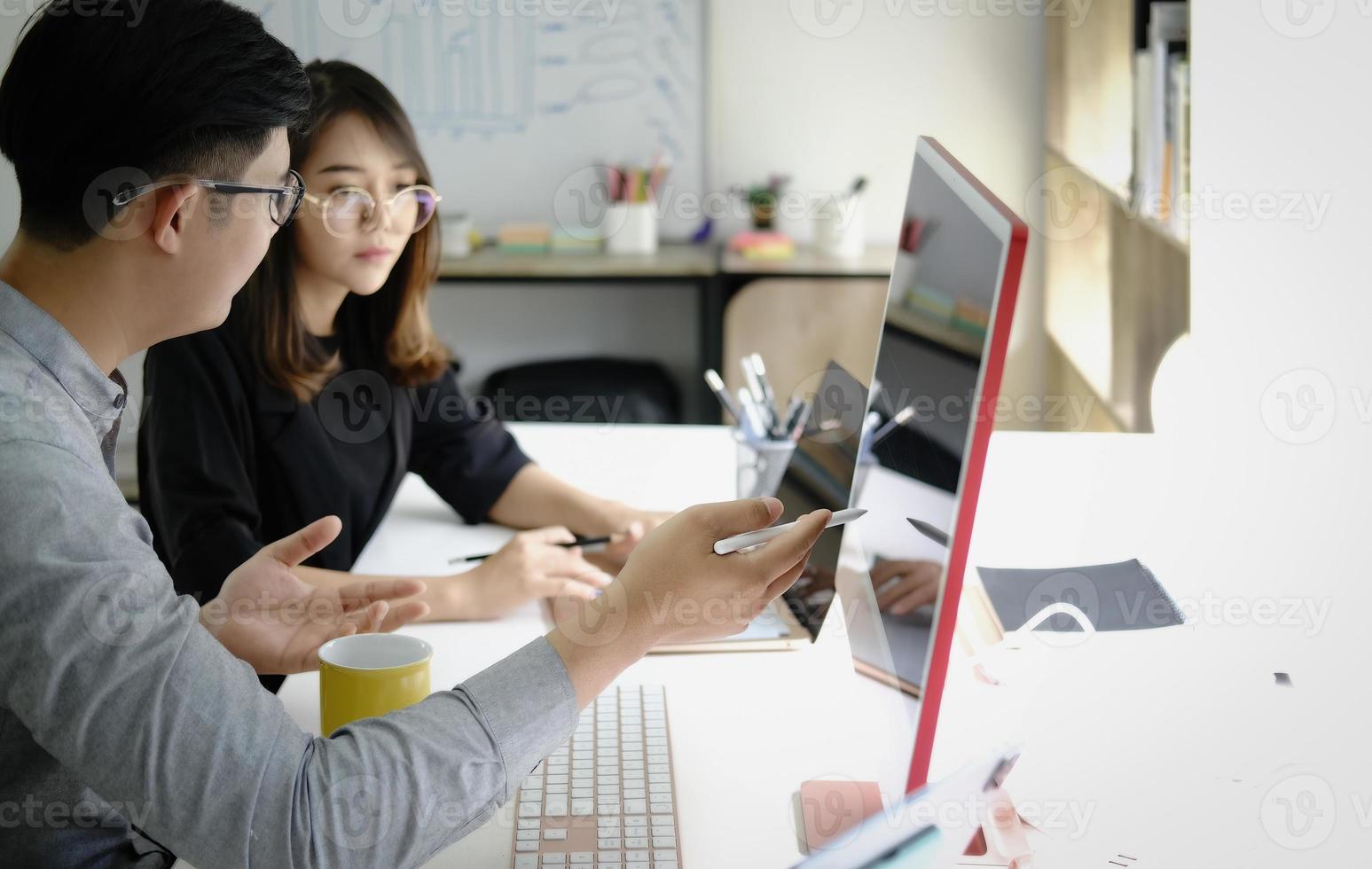 An investment expert points a pen at a computer monitor to analyze the stock market to teach you how to make a profit. photo