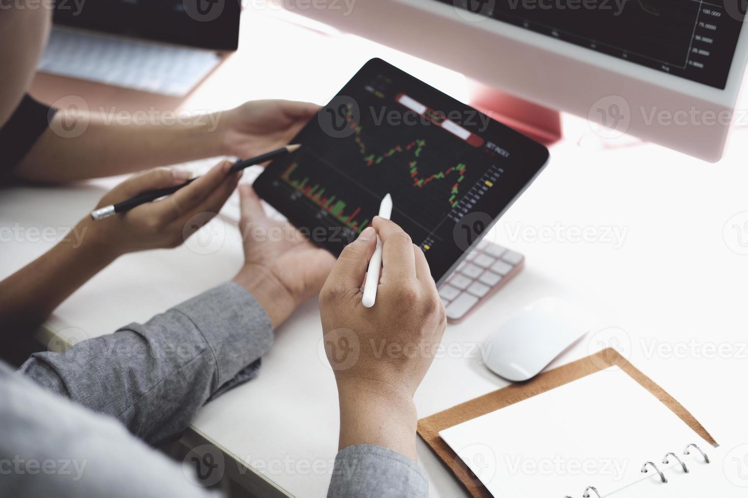 An investment expert points a pen at a computer monitor to analyze the stock market to teach you how to make a profit. photo