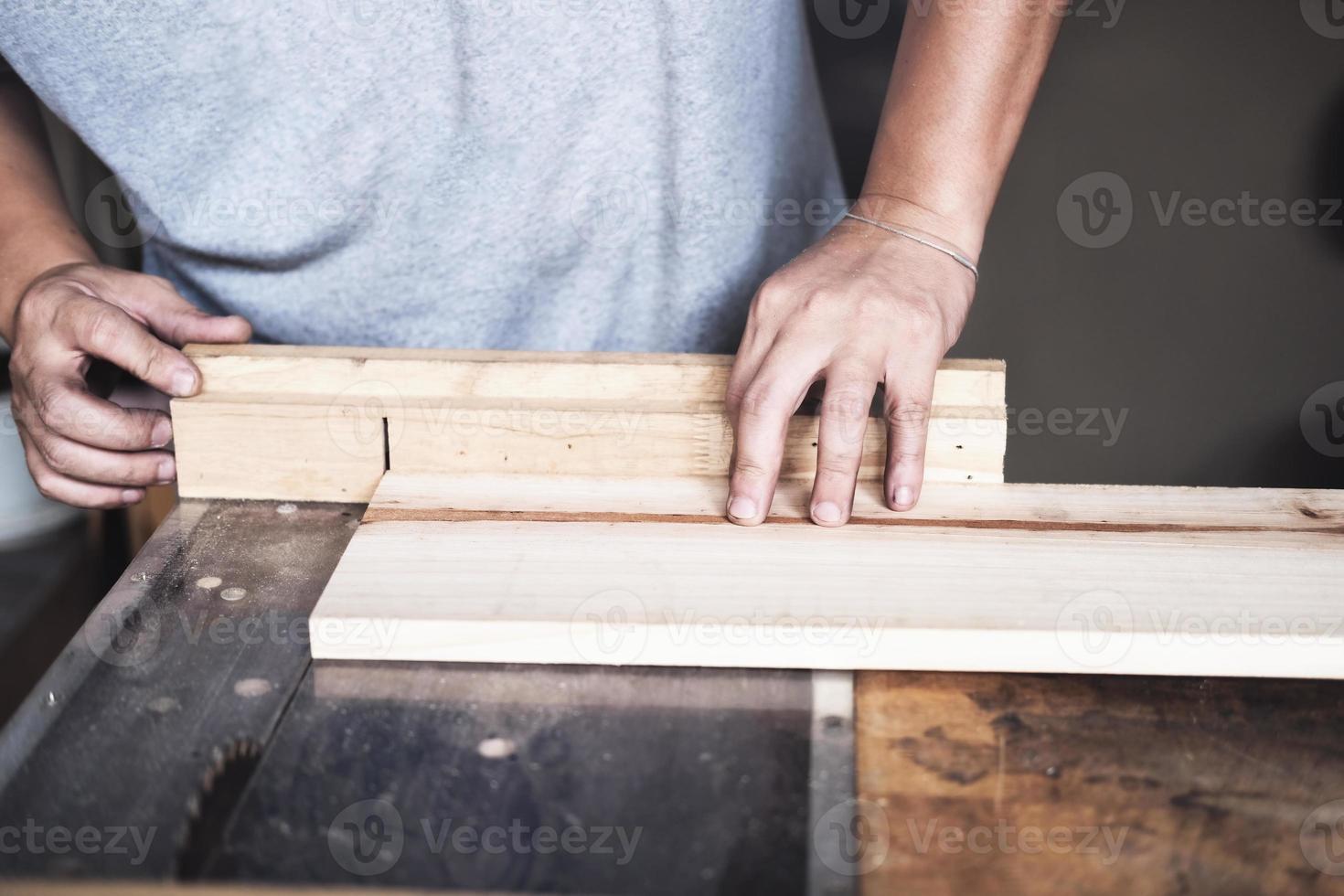 Woodworking practitioners use saw blades to cut wood pieces to assemble and build wooden tables for their clients. photo