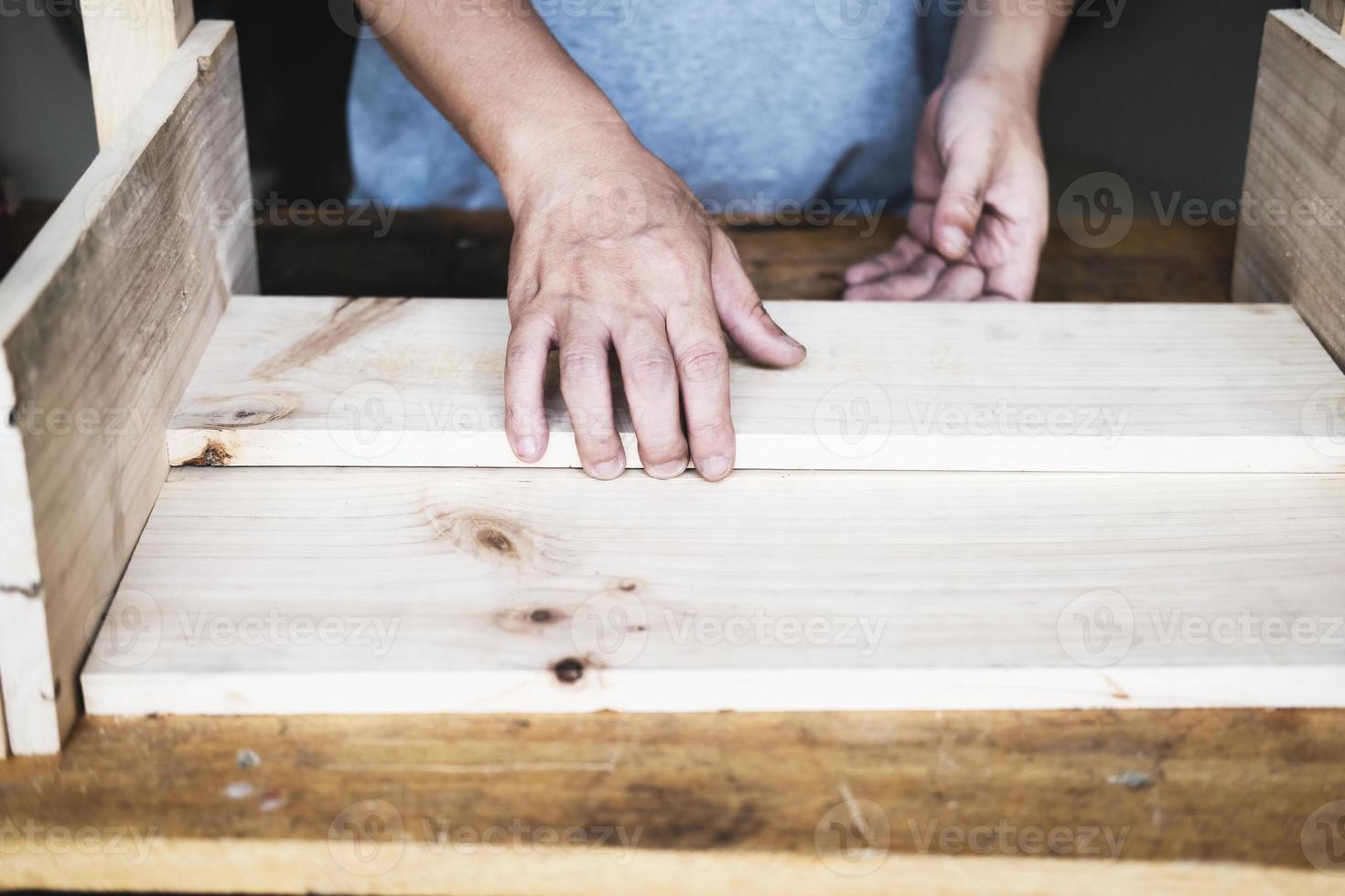 A carpenter measures the planks to assemble the parts, and build a wooden table for the customer. photo