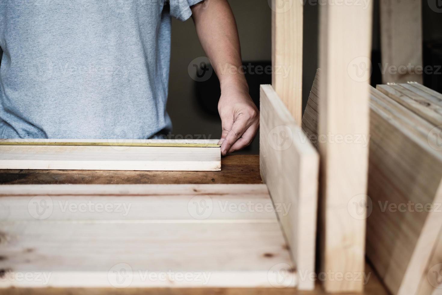 do-it-yourself concept Craftsmen use a tape measure to assemble wooden pieces to make wooden tables for customers. photo