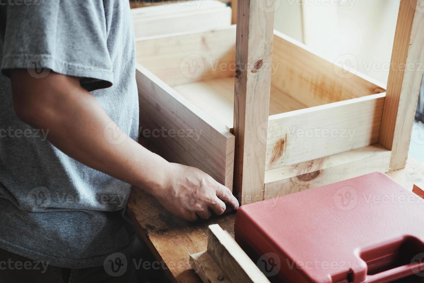 A carpenter measures the planks to assemble the parts, and build a wooden table for the customer. photo