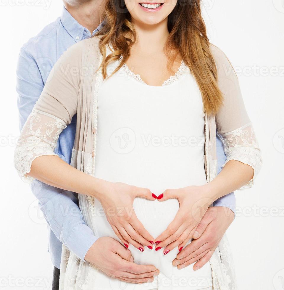 couple making a heart shape on the pregnant belly with their hands. Concept of pregnancy, expecting a baby, love, care,cropped photo