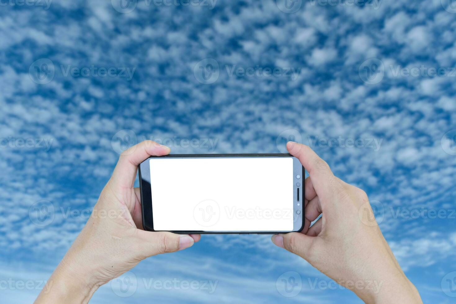 Hand holding smartphone blank screen over blue sky cloud. photo