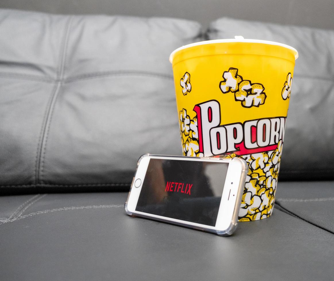 sao paulo, brasil, mayo de 2019 -sofá con botella de palomitas de maíz y logotipo de netflix en el teléfono de Apple. netflix es un proveedor global de transmisión de películas y series de televisión. foto