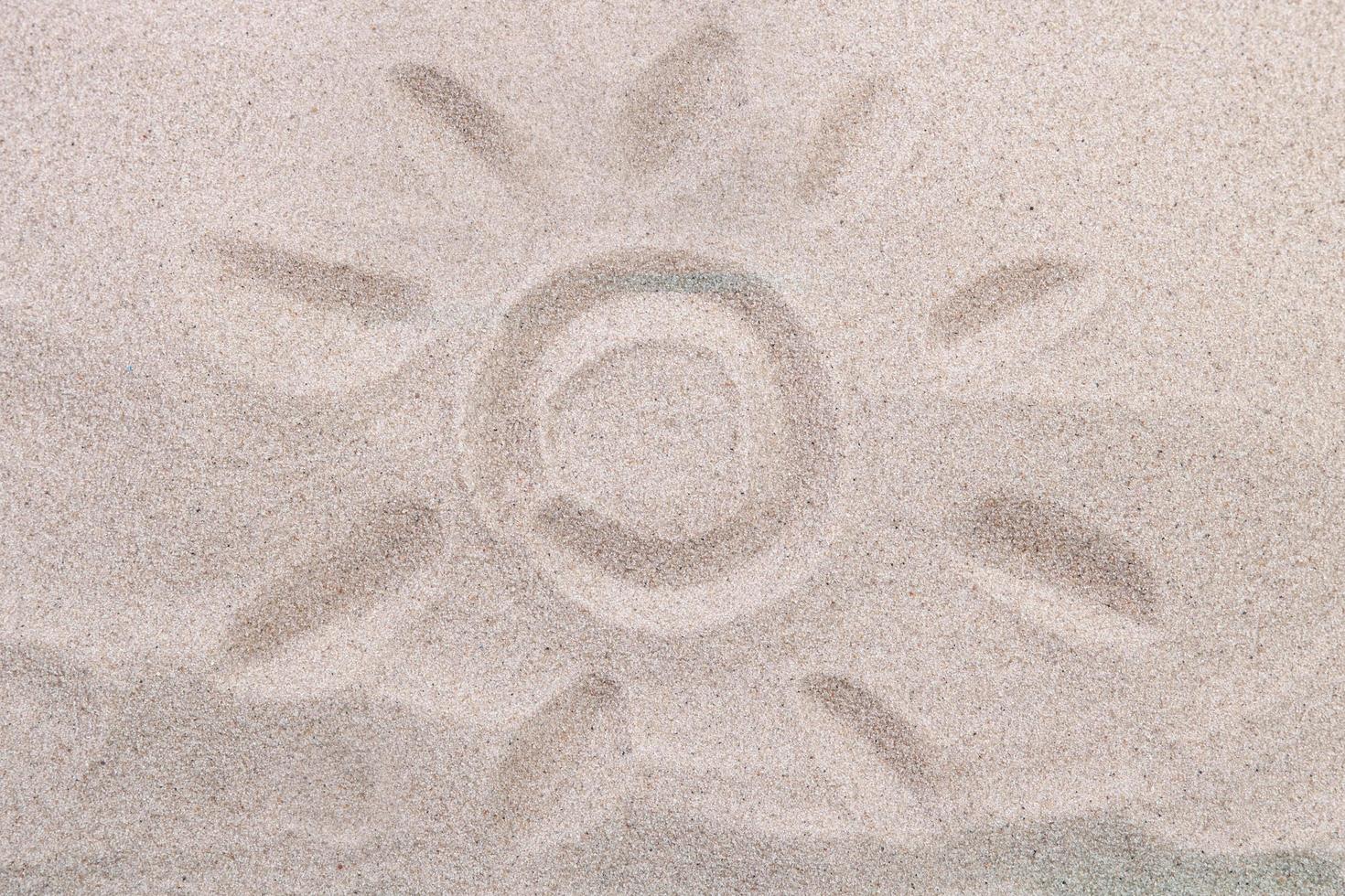 Drawing of the sun on the sand top view photo