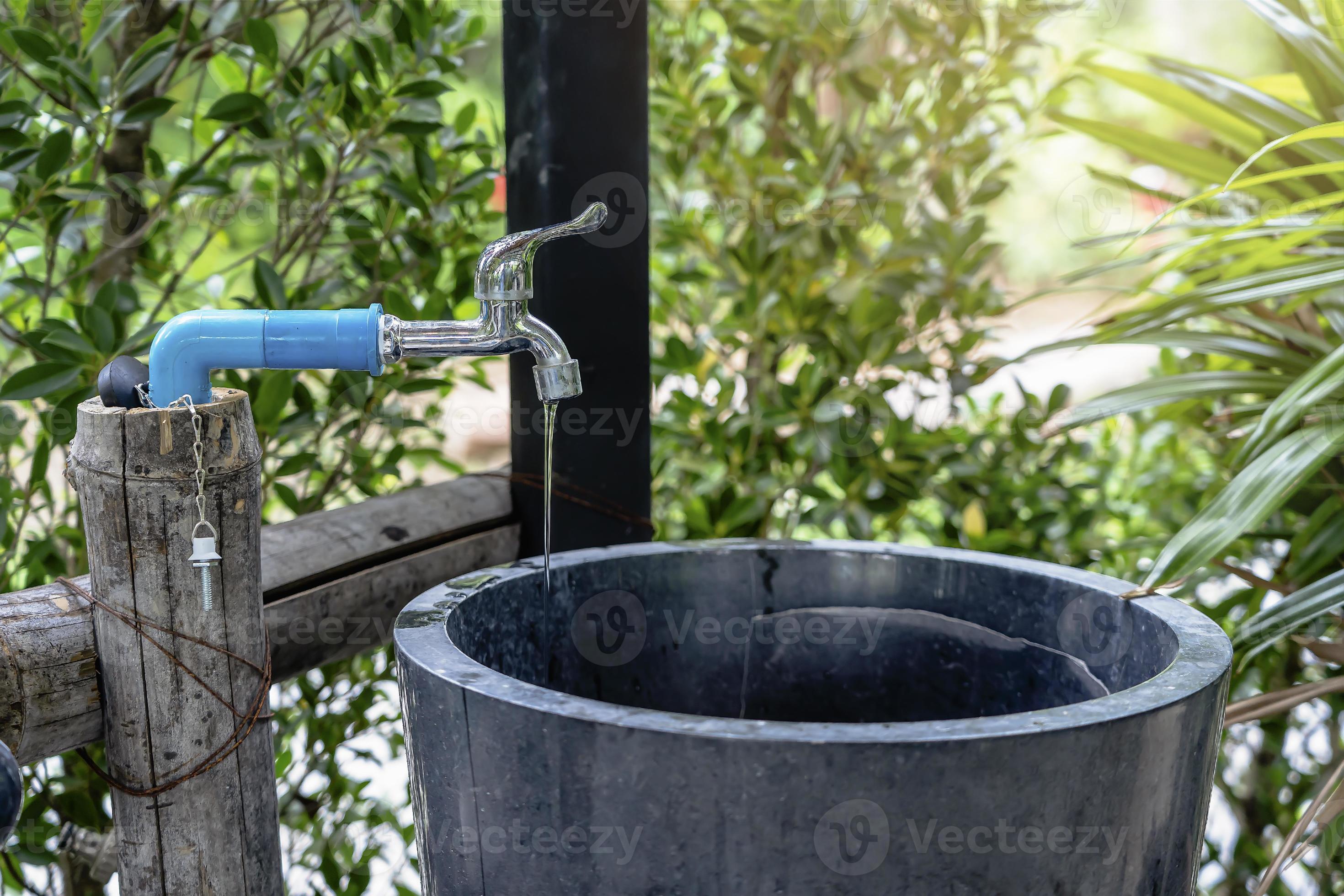 Closeup of a water tap or faucet leaking drop of water with green background Wash Basin at