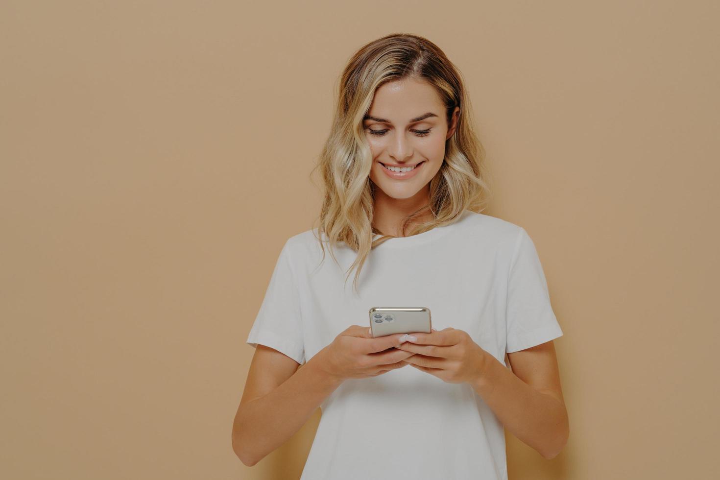 Young happy girl using smartphone, chatting with boyfriend in social media and smiling photo