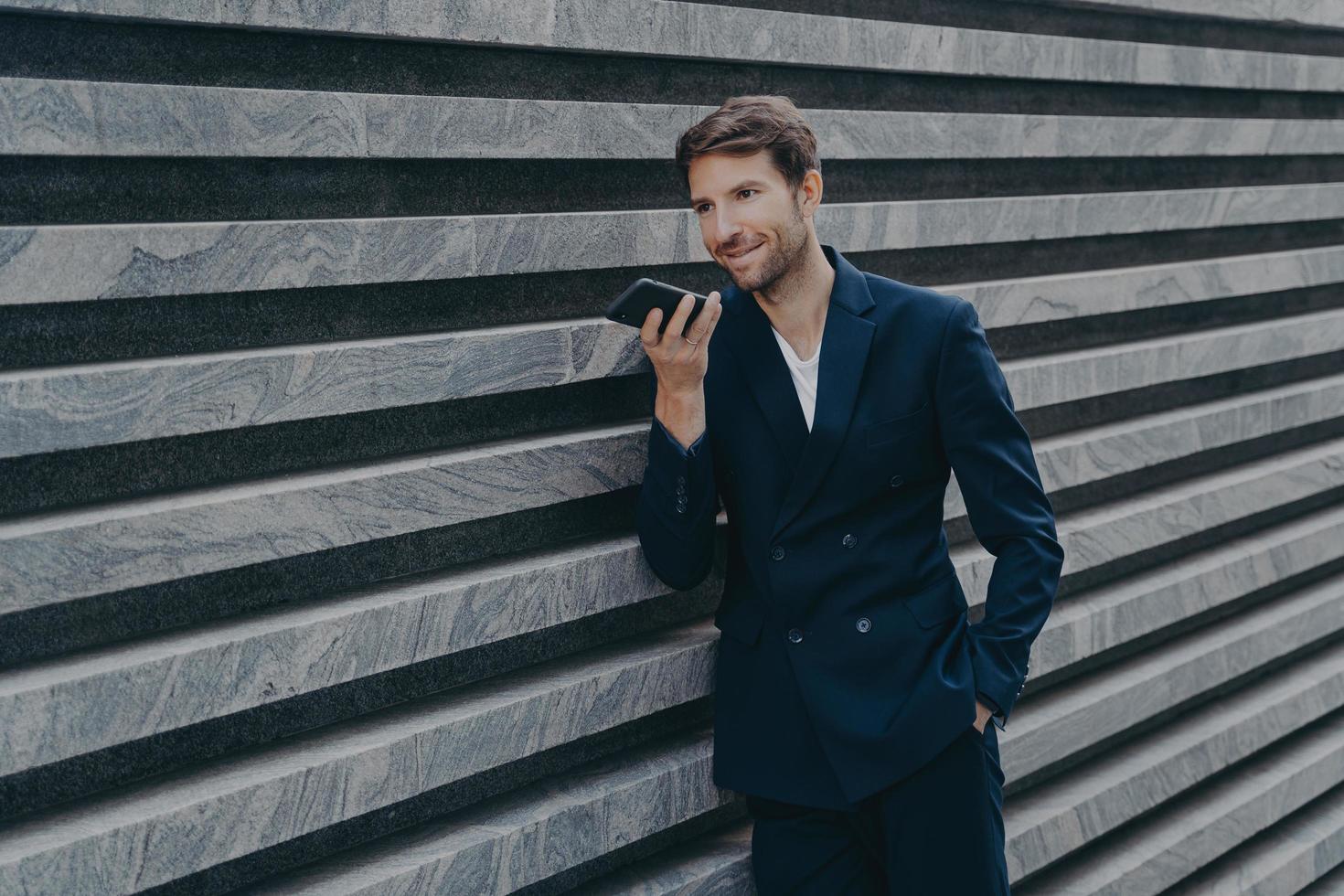 Professional prosperous adult man with stubble uses loudspeaker answers incoming call photo