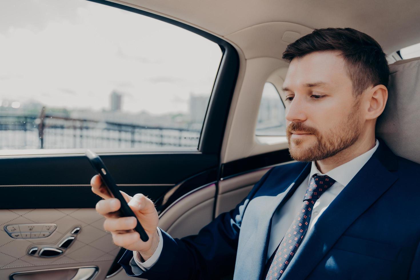 Investor checking his phone while riding in limousine photo