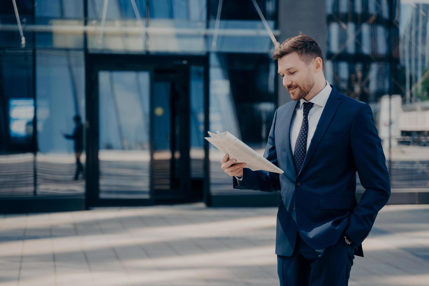 Male lawyer reading newspaper while walking to firm photo