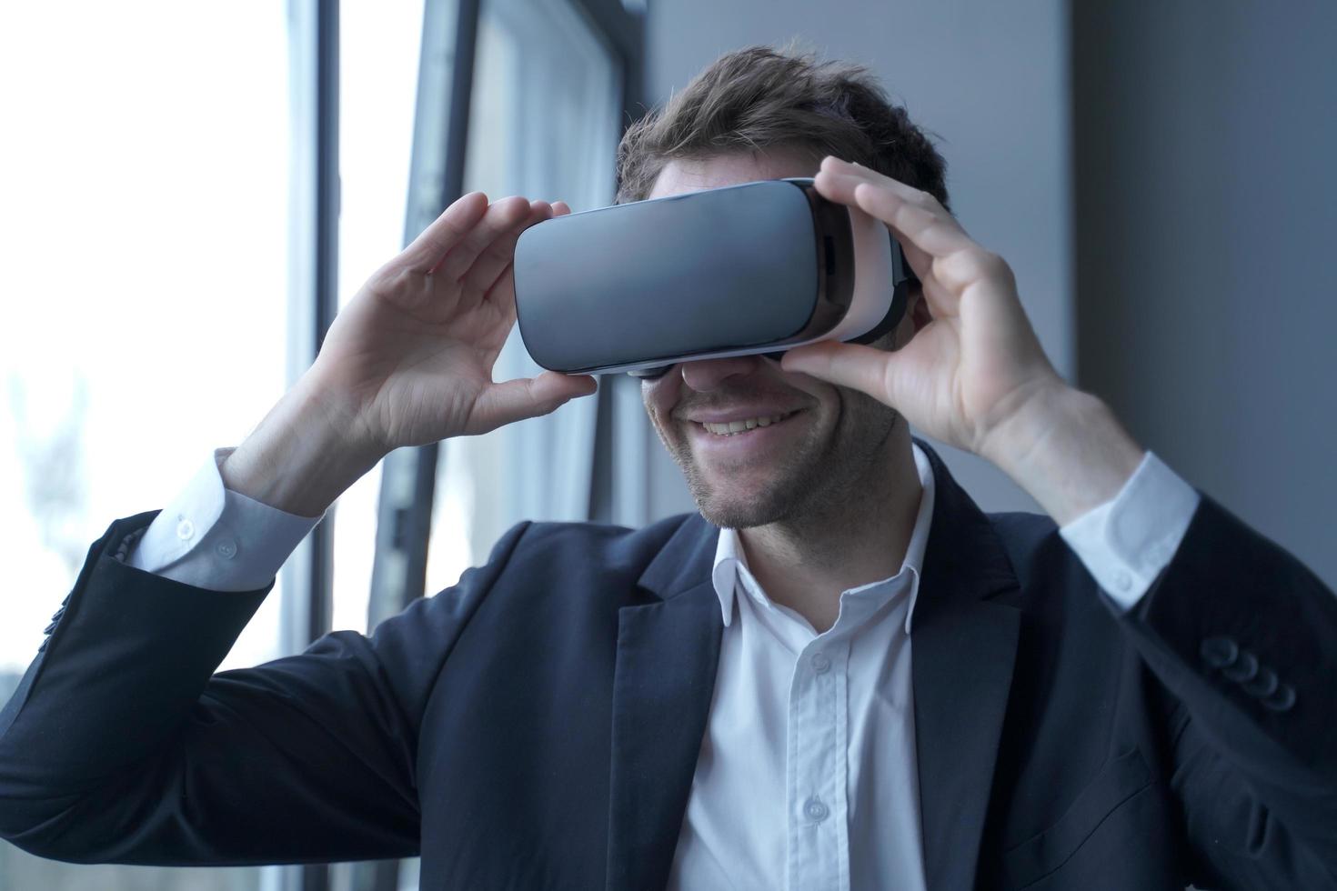 Excited business person in suit wearing VR headset on head taking part in meeting in virtual reality photo