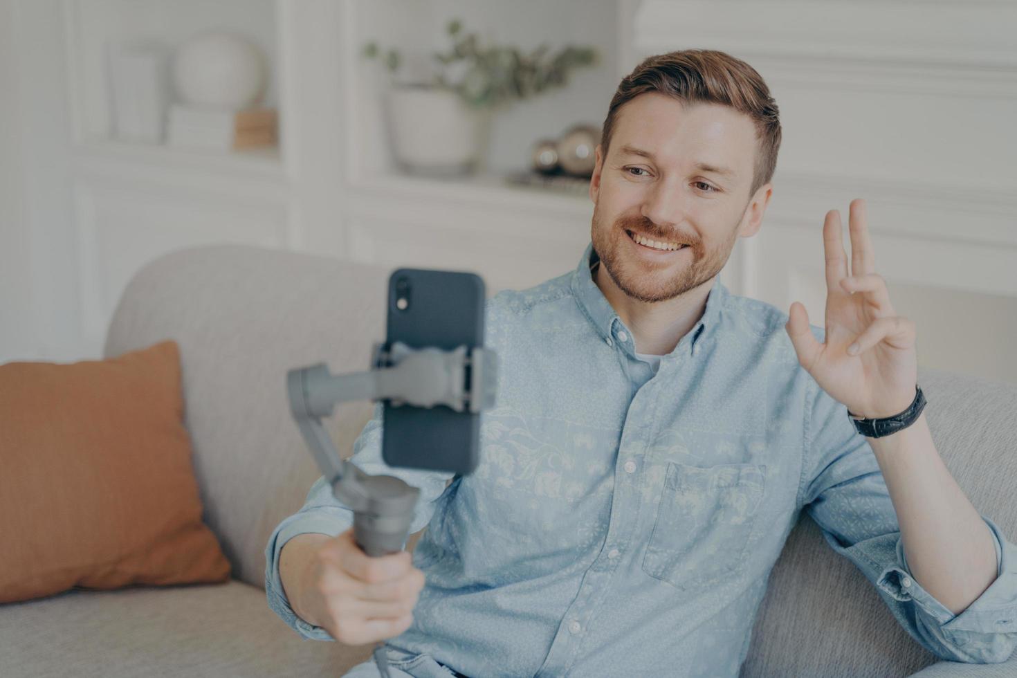 Young man talking with his friend through online video chat using telephone photo