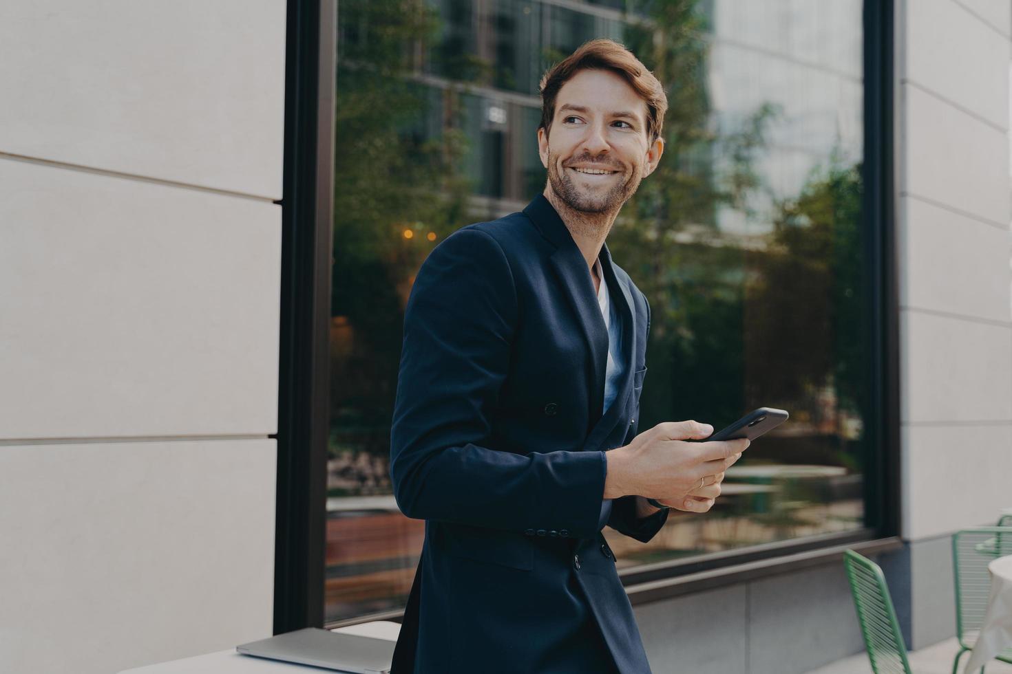 Pleased male director checks personal organizer via smartphone waits for message or call photo