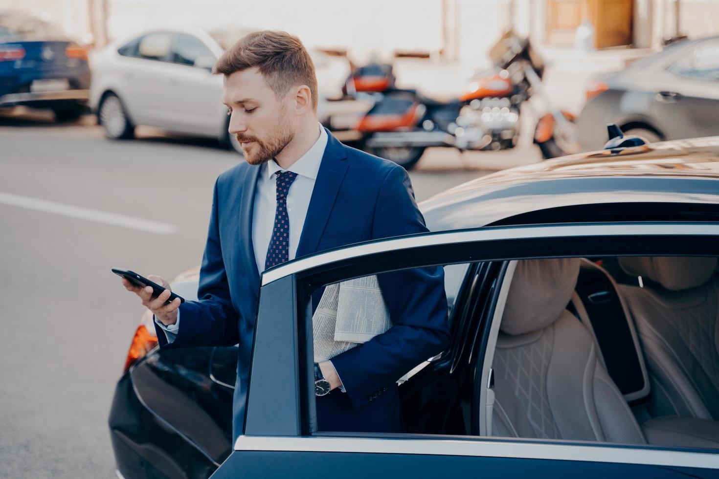 Successful executive manager in formal stylish tuxedo suit getting out of car photo