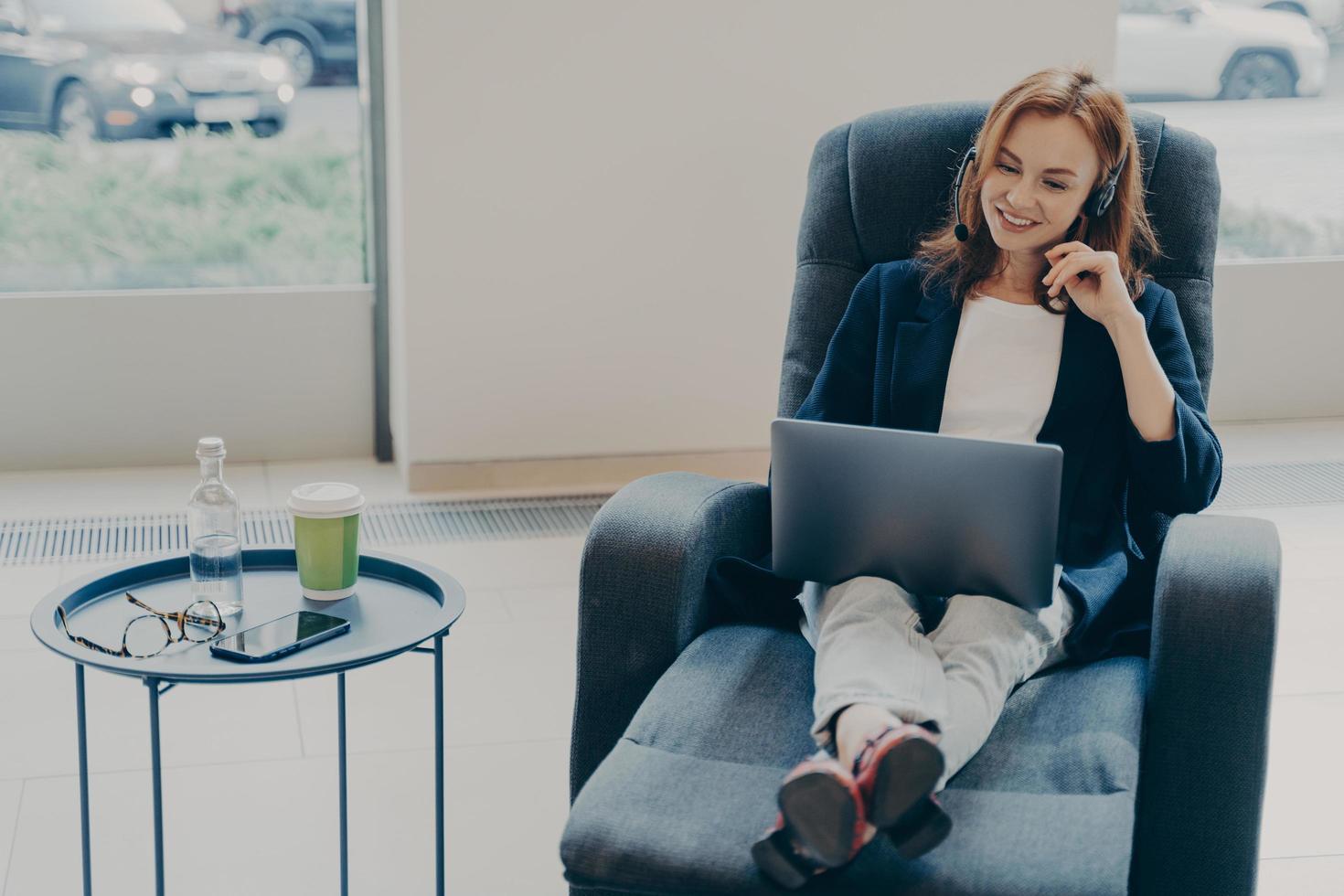 Successful redhead woman entrepreneur talking online with coworkers while working remotely at home photo