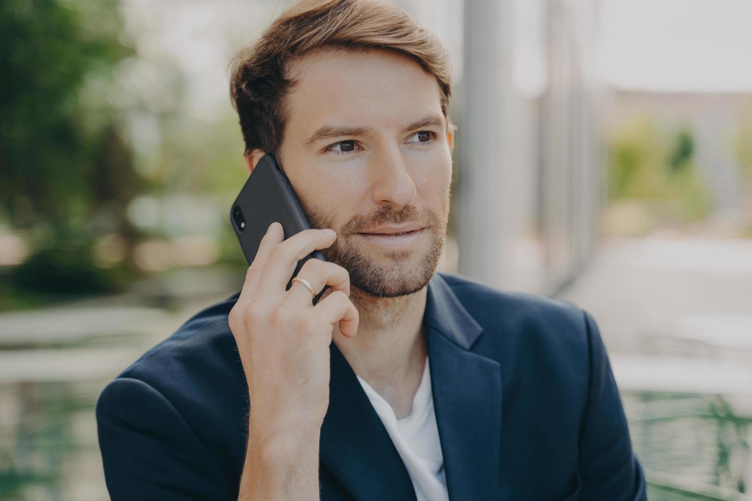 Horizontal shot of male entrepreneur or manager consults client by telephone call photo