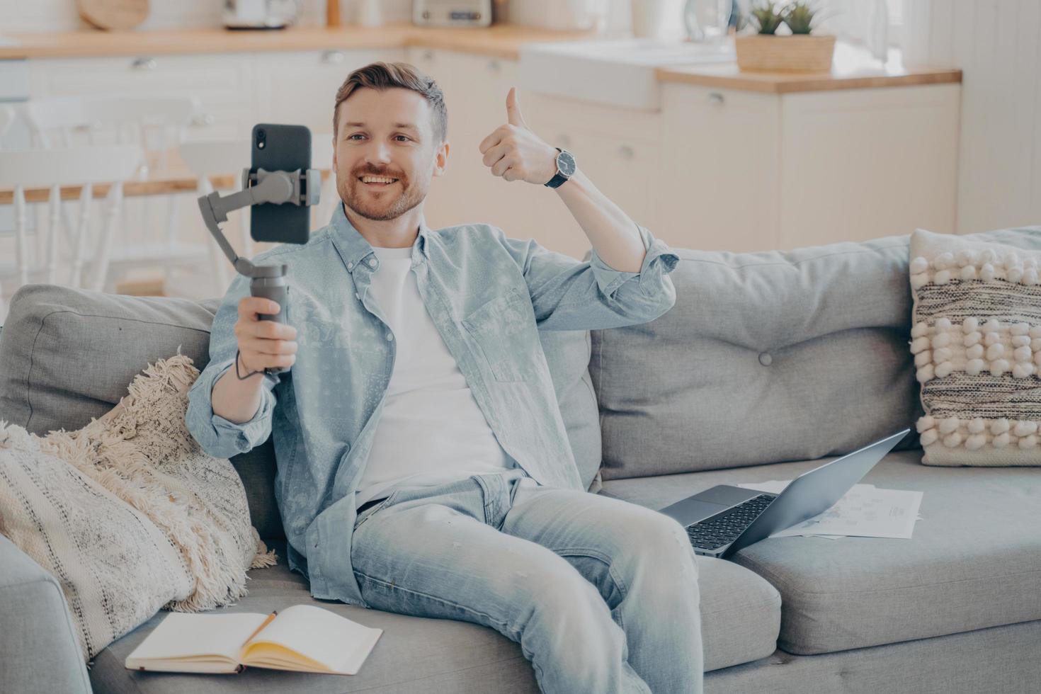 Confident young male freelancer showing thumbs up gesture to his client in video call photo