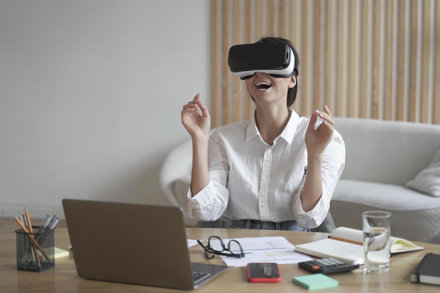 Lady entrepreneur in VR headset sitting at desk at home office interacting with 3d visualization photo