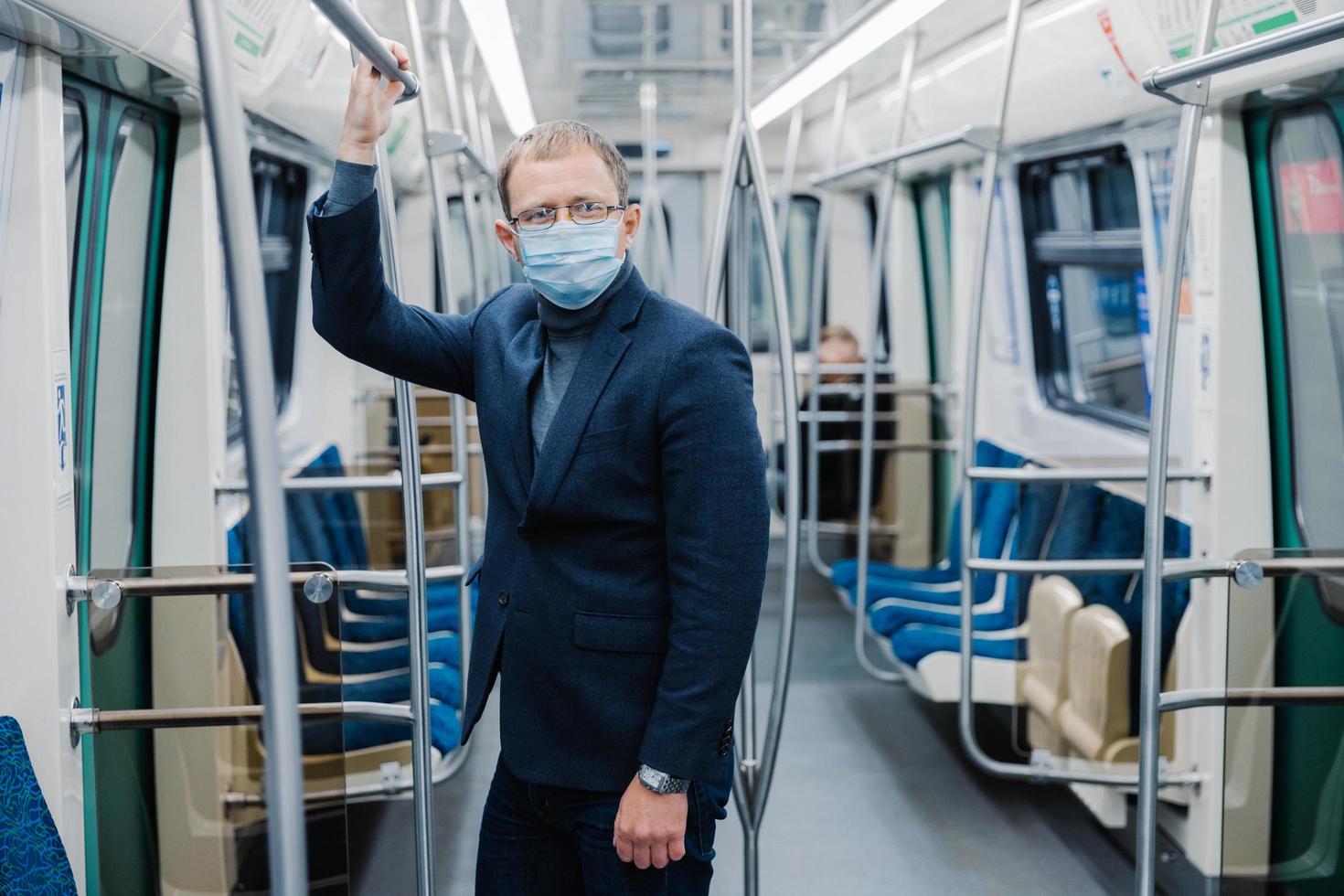 Coronavirus crisis in 2020. Man commutes to work in empty underground, uses public transport, uses protective face mask against virus, wears protective surgical mask during quarantine period photo