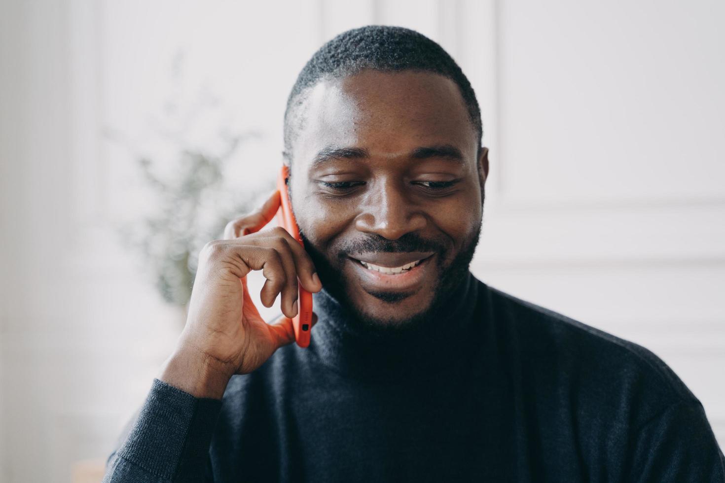 Young smiling african man having business conversation on mobile phone photo