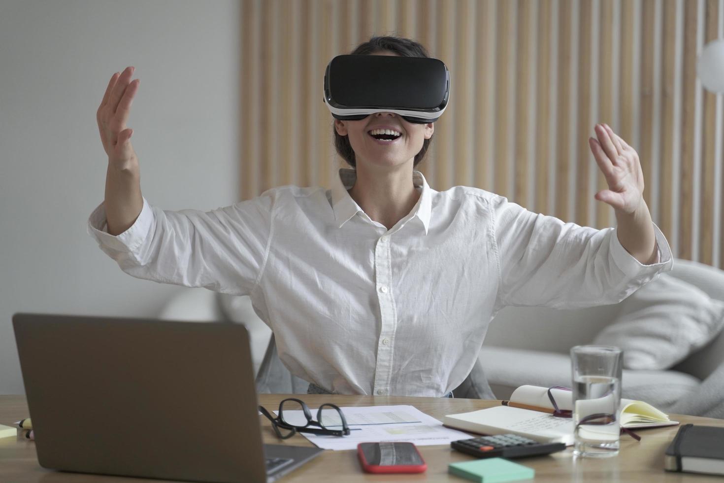 Excited european business woman testing VR glasses at work photo