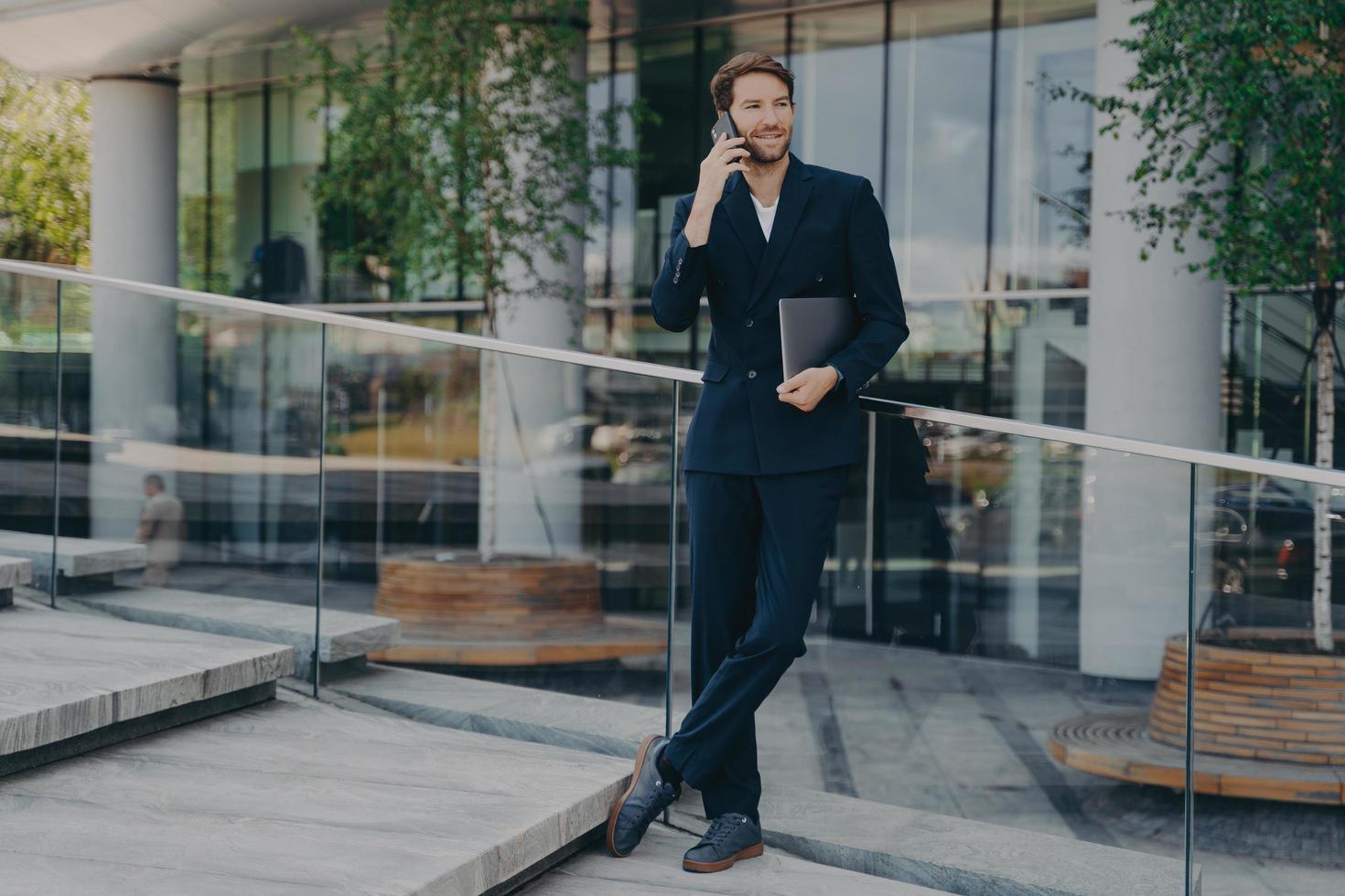 Full length shot of elegant businessman in formal clothes has telephone conversation photo