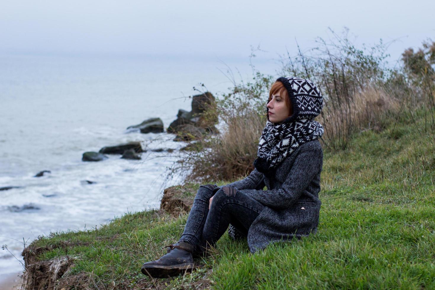 mujer joven en abrigo gris contra el fondo del mar de otoño foto