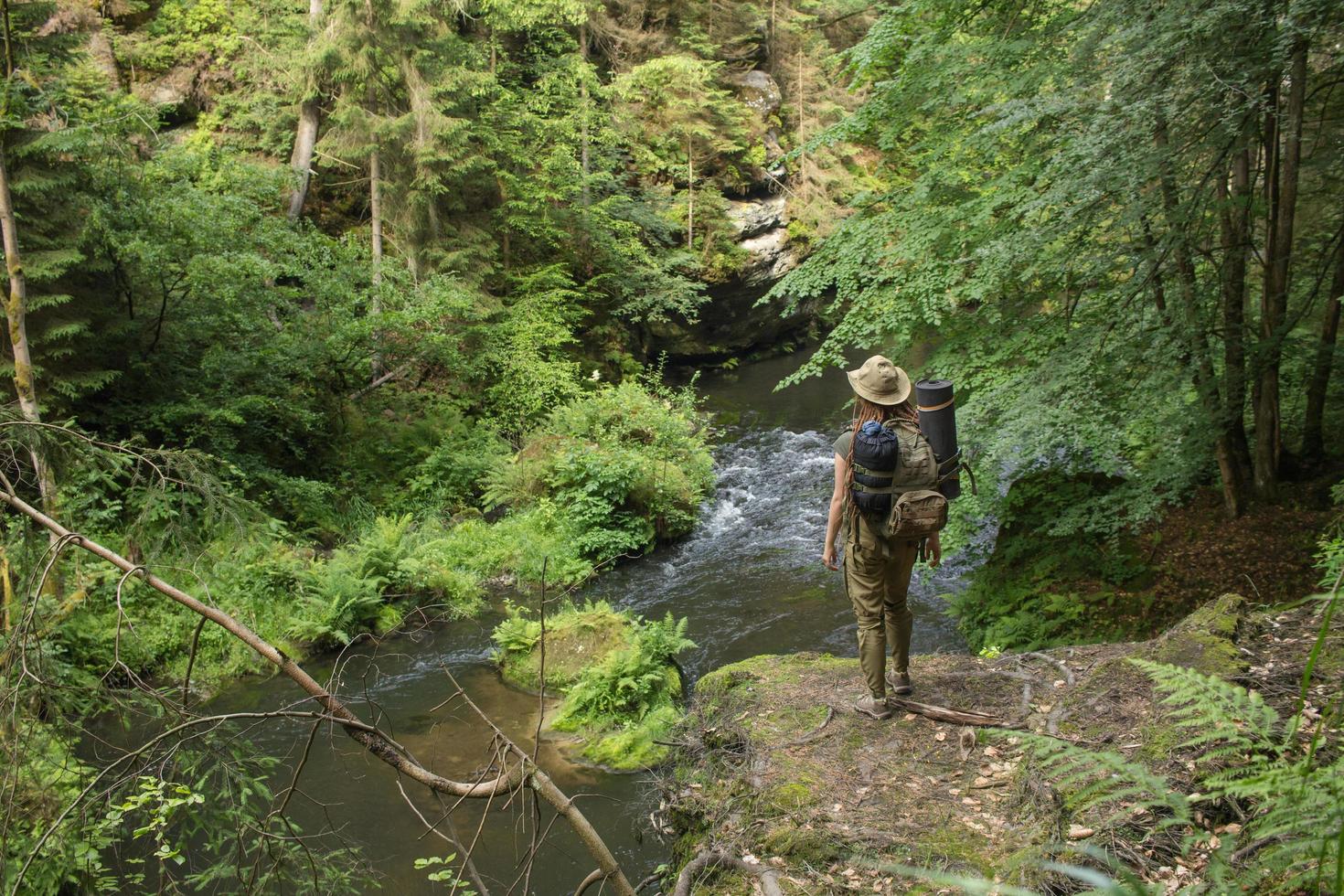 Young woman hiker posing near the river in bohemian switzerland national park, female traveler in mountains of czech republic photo