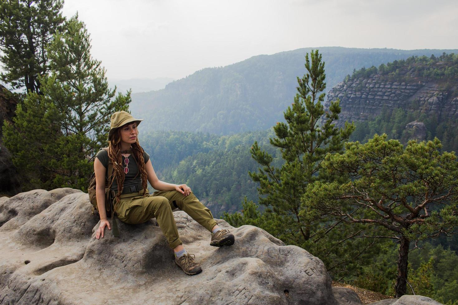 Young woman hiking on the spring meadow, mountains and forest on background photo