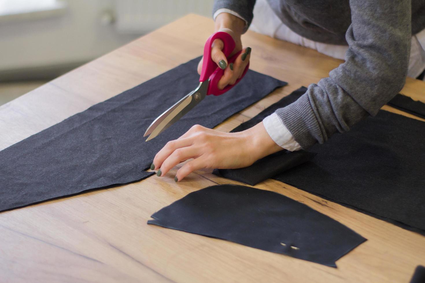 seamstress at work on the table, tailor woman work in studio with clothes photo