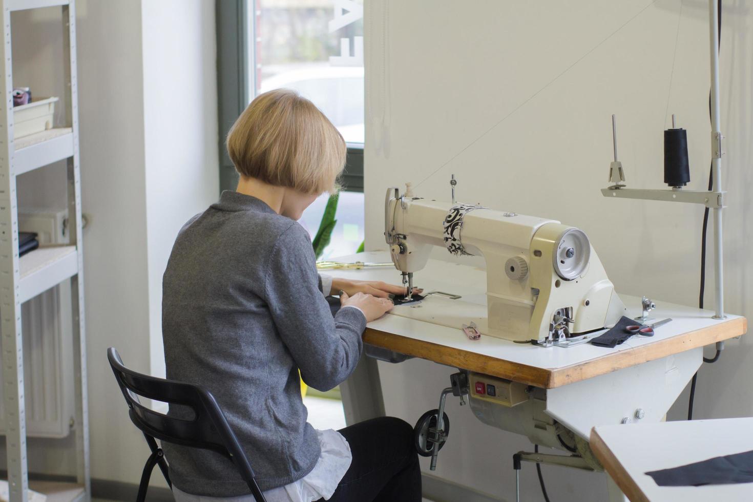 seamstress at work on the table, tailor woman work in studio with clothes photo