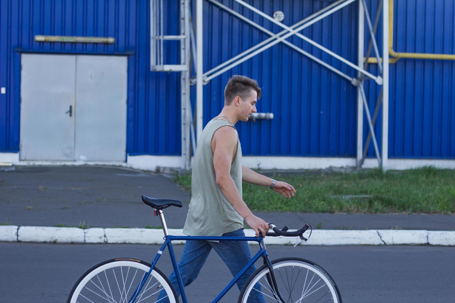 joven, hombre camina con bicicleta fixie, fondo urbano, foto de hipster con bicicleta en colores azules