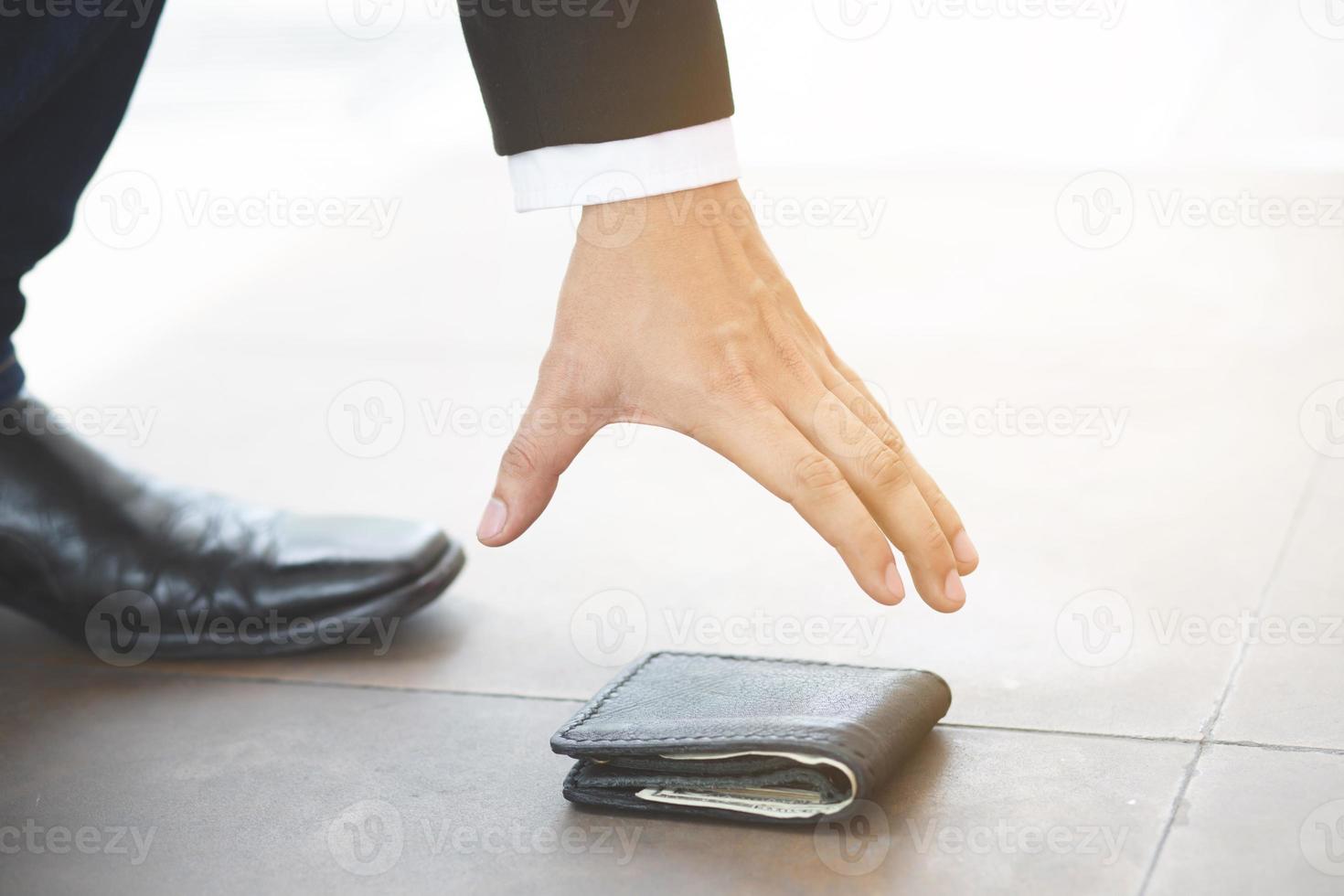 Close of a person picking up a lost wallet on the ground photo