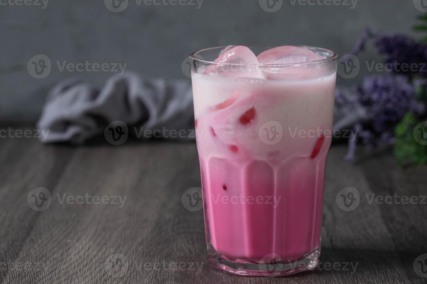 bebida fría de leche rosa fría en vidrio transparente sobre fondo gris. leche tailandesa foto