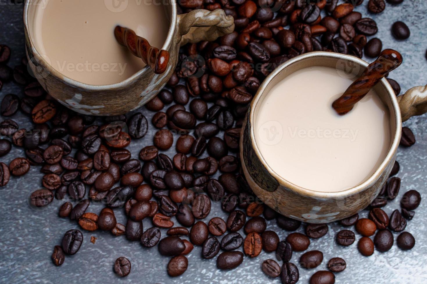 Two mugs of coffee with coffee beans on a dark backdrop. photo