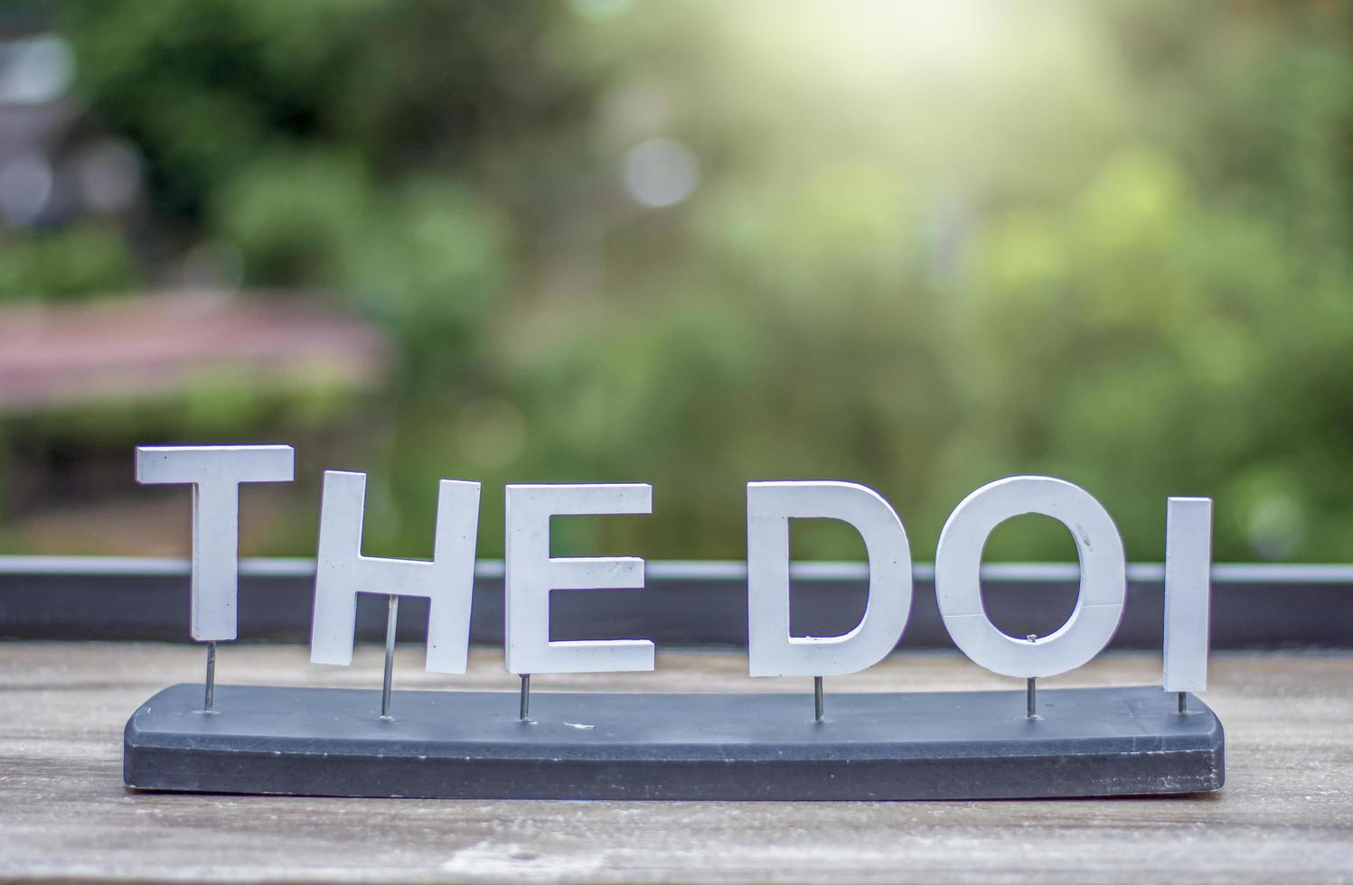 THE DOI letter sign on wooden table blur background and nature photo