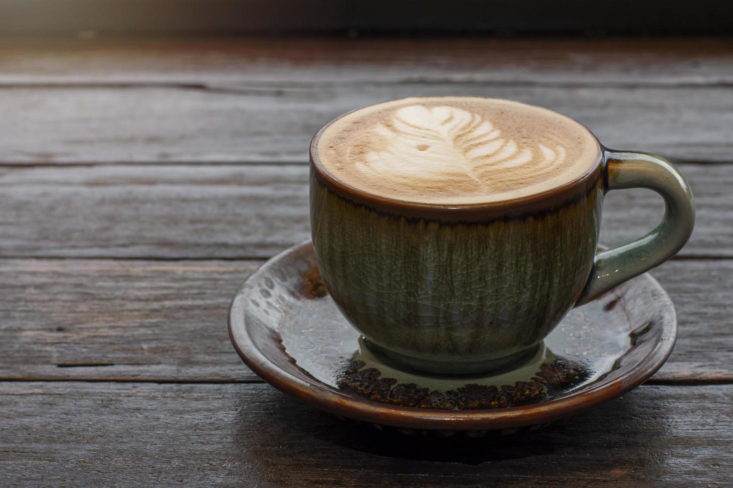 coffee in green cup on wooden table in cafe photo